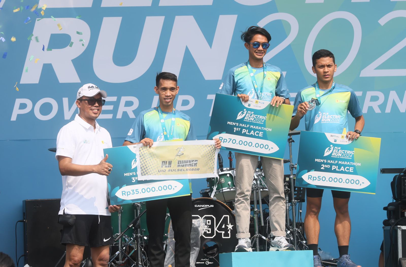 Penyerahan penghargaan untuk pemenang kategori Men’s Half Marathon PLN Electric Run 2024. Keterangan foto: Direktur Transmisi dan Perencanaan Sistem PLN, Evy Haryadi (kiri), juara 1 Men’s Half Marathon, Robi Syianturi (kedua dari kanan), juara 2 Men’s Half Marathon, Rikki (kanan), dan juara 3 Men’s Half Marathon, Syamsuddin Massa (kedua dari kiri).